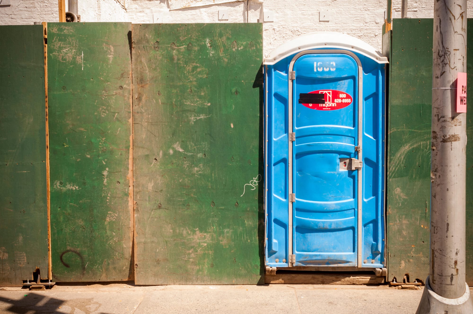 A porta potty installed along the side of a construction site